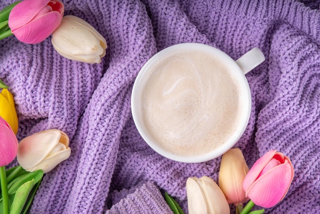 Frühlingskaffee-Hintergrund mit Blumen und gestricktem Pullover
