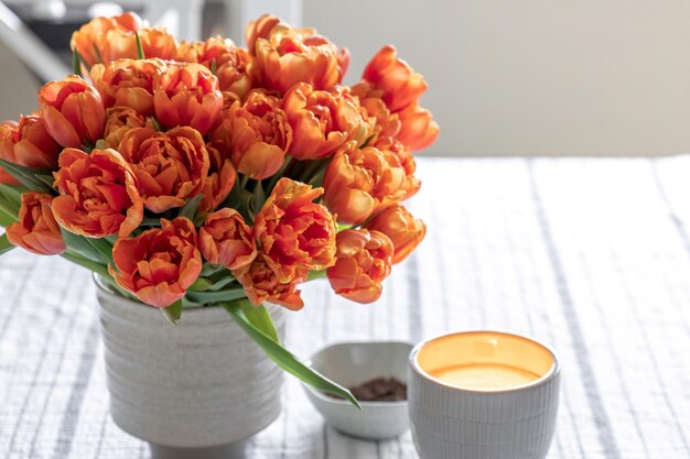 Frühlingskomposition mit einem Strauß orangefarbener Tulpen im Inneren des Hauses