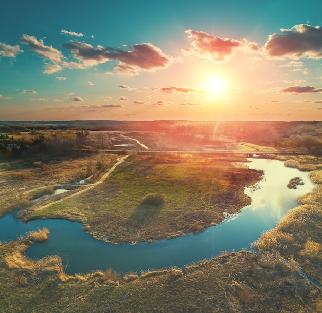 Frühlingslandschaft am Abend, Luftbild. Panoramablick auf den Fluss auf der Wiese bei Sonnenuntergang. Panorama aus 9 Bildern