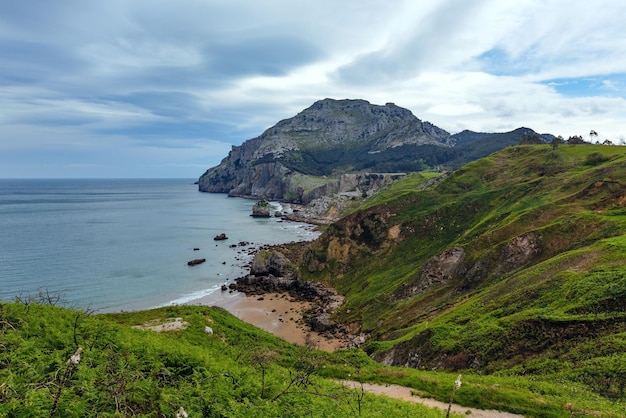 Frühlingsmeerküstenlandschaft mit felsigem Kap und Sandstrand (San Julian Beach, Liendo, Kantabrien, Spanien).