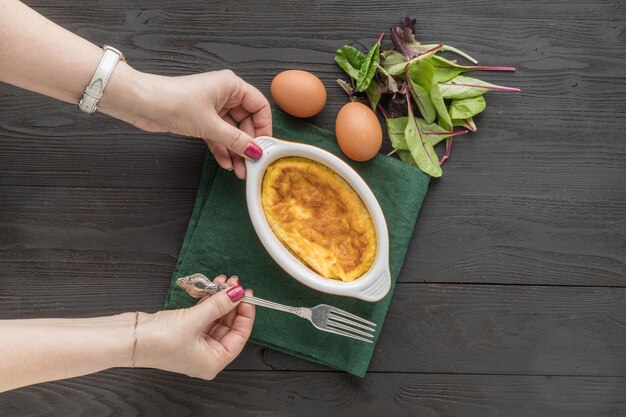 Frühlingsomelett mit Grün für Kind in einer Pfanne über rustikaler Holzoberfläche