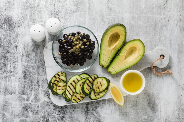 Frühlingssalat aus reifer Avocado, gegrillter Zucchini, schwarzen Oliven, Kapern und Zitronendressings