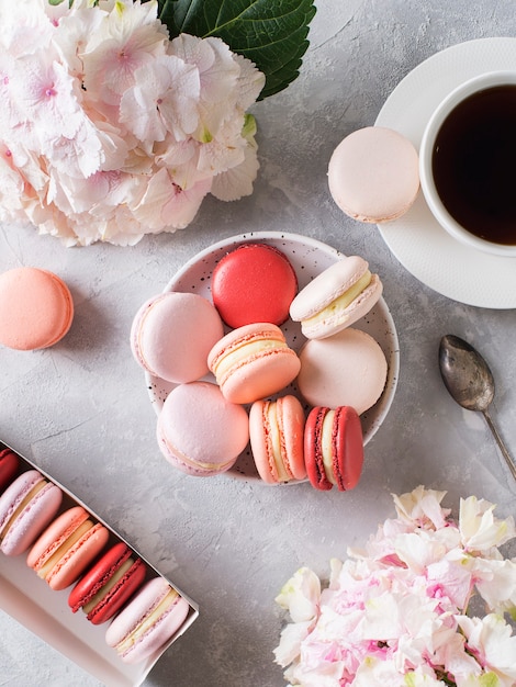 Frühlingsstimmung Stillleben mit Makronen, Blumen und einer Tasse Kaffee auf Grau