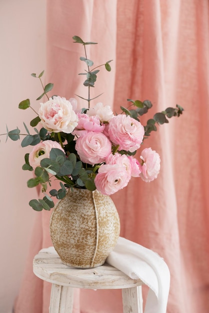 Frühlingsstrauß aus Pfingstrosen und Ranunculus in einem selektiven Fokusbild der beige Vase