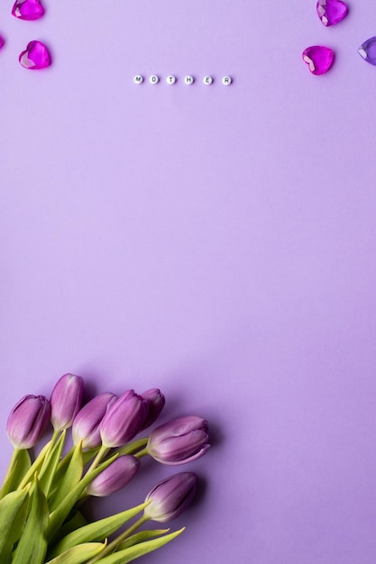 Frühlingstulpen und Inschrift Mutter aus mehrfarbigem Würfel auf violettem Hintergrund