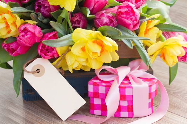 Frühlingstulpen und Narzissenblumen mit Geschenkbox und leerem Etikett