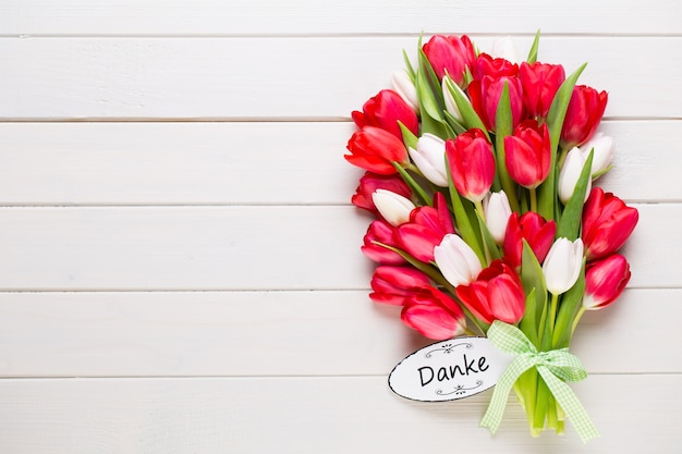 Frühlingszeit. Roter Tulpenstrauß auf dem weißen hölzernen Hintergrund.