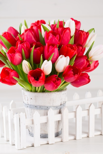 Frühlingszeit. Roter Tulpenstrauß auf dem weißen hölzernen Hintergrund.