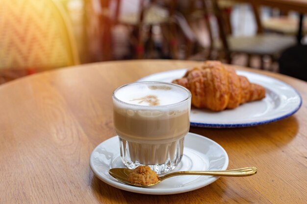 Frühstück am Morgen, Kaffee Latte und Schokoladencroissant auf Café-Hintergrund