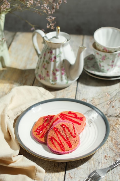 Frühstück am Morgen mit rosa Pfannkuchen und Tee