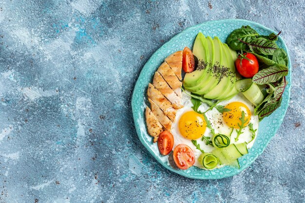 Frühstück Avocado Eier Kirschtomaten Hühnchen gegrillte Filetgurken Ketogene Diät Frühstücksort für Text Draufsicht