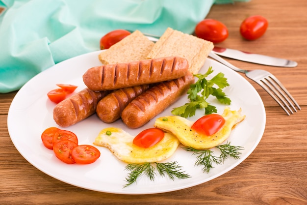 Frühstück fertig. Bratwürste, Rührei, Tomaten und Gemüse.