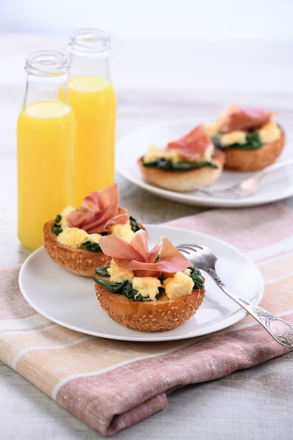 Frühstück. Gebackenes Brötchen mit Käse, Spinat, Schinken und Orangensaft