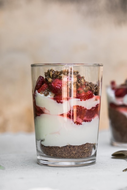 Frühstück geschichtetes Parfait-Dessert mit Joghurtschwammkeks und frischem Erdbeerweißhintergrund-Kopienraum