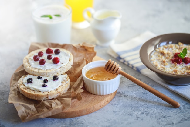 Frühstück. Getreidebrot mit Hüttenkäse und Beeren, mit Müsli und Orangensaft und Naturjoghurt. Richtige und gesunde Ernährung.