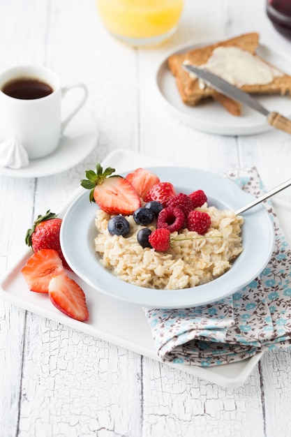 Foto frühstück haferbrei mit früchten beeren und kaffeetasse.