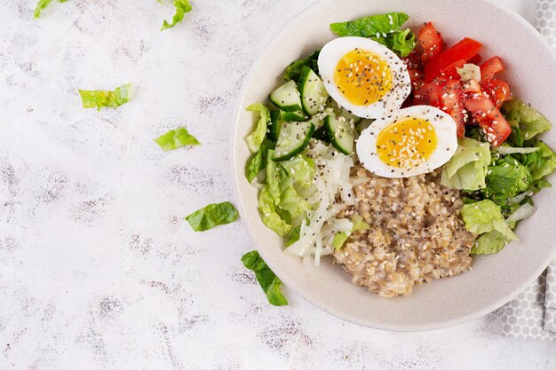 Frühstück Haferbrei Porridge mit gekochten Eiern Tomaten Gurke und Zwiebeln Gesundes ausgewogenes Essen Modisches Essen Top View Flat Lay