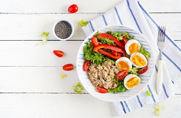 Frühstück Haferflockenbrei mit grünen Kräutern, gekochtem Ei, Tomaten und Paprika. Gesundes ausgewogenes Essen. Draufsicht, Overhead, Speicherplatz