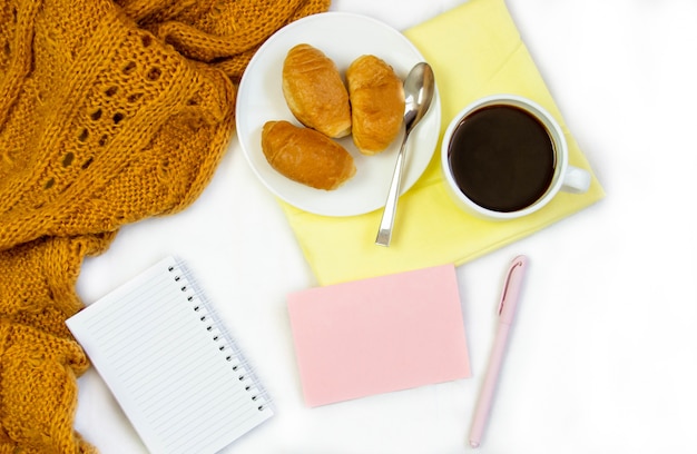 Frühstück im Bett. Flache Komposition mit Kaffee, Croissants und einem Notizbuch zum Schreiben. Lifestyle-Rahmen. Draufsicht auf Blätter