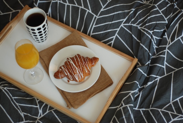 Frühstück im Bett. Kaffee, Croissants und Orangensaftglas.