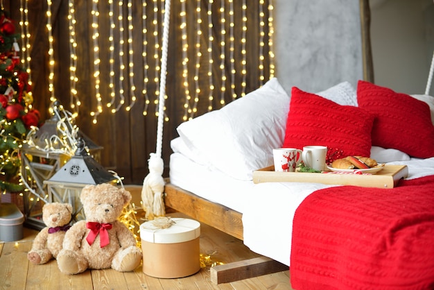 Frühstück im Bett, Tablett mit Kaffee und Croissant. Modernes Schlafzimmer Interieur. Romantische Morgenüberraschung.