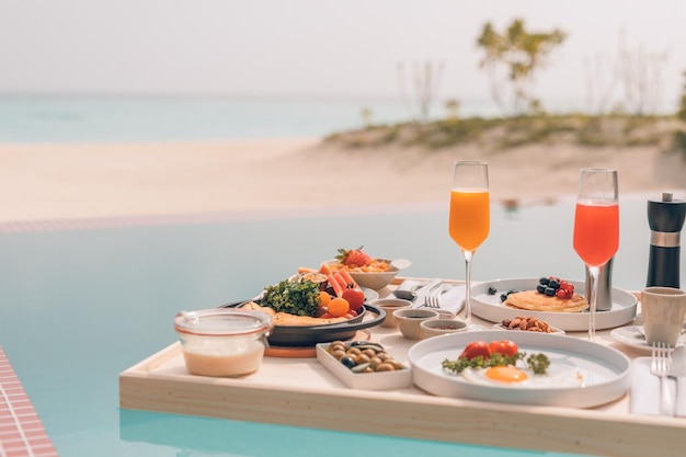 Frühstück im Swimmingpool, schwimmendes Frühstück im luxuriösen tropischen Resort. Entspannender Tisch am Pool