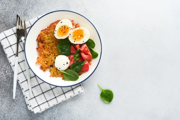 Frühstück Kartoffeln Latkes mit Sauerrahm-Spinat-Salat-Tomaten und gekochten Eiern auf hellem Hintergrund Leckeres Essen zum Frühstück Draufsicht