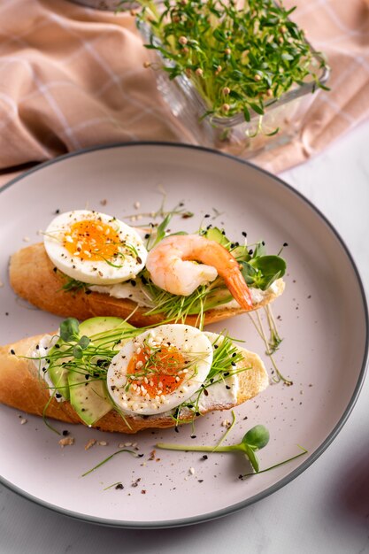 Frühstück mit Bruschetta mit Garnelen, Eiern und Microgreens in einem Teller, Nahaufnahme