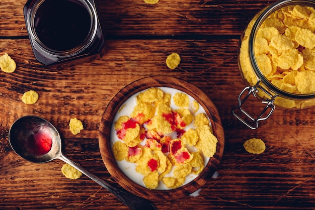 Frühstück mit Cornflakes, Milch und Beerensirup. Sicht von oben