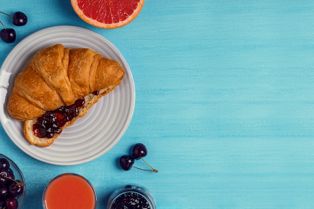 Frühstück mit Croissant, Marmelade, Obst und Saft.