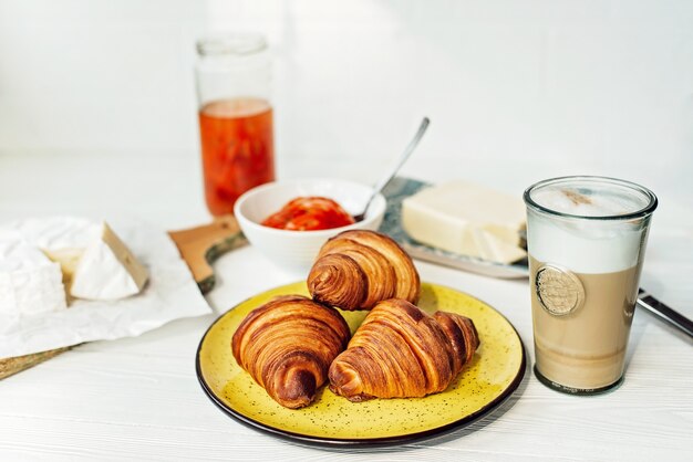 Frühstück mit einem frischen Croissant und einer Tasse aromatischem Kaffee Latte, Mandarinenmarmelade