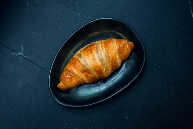 Frühstück mit frischen Croissants auf schwarzem Teller