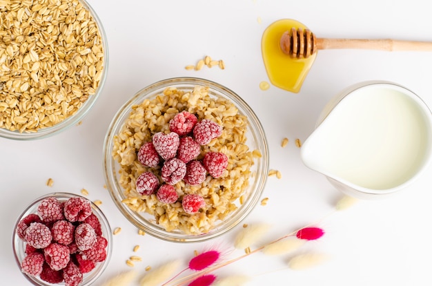 Frühstück mit Haferbrei Schüssel mit Himbeeren und Honig Schöpflöffel auf weiß