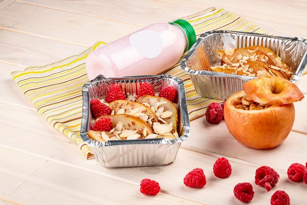 Frühstück mit Haferbrei und gebackenem Obst in Behältern auf weißem Holzhintergrund Diät zum Mitnehmen und gesunde Ernährung