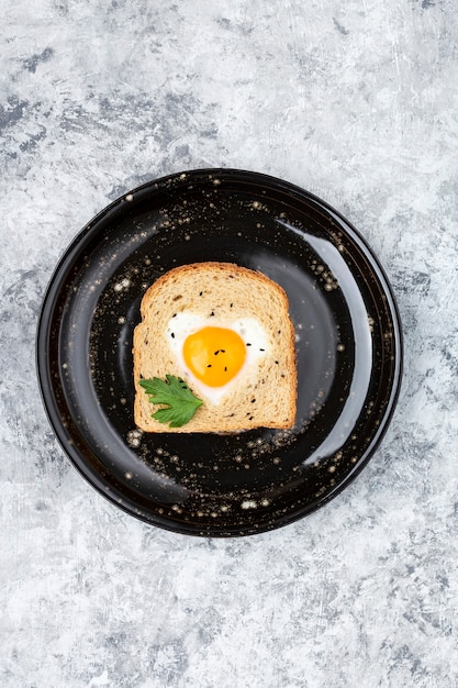 Frühstück mit herzförmigem gekochtem Ei auf einer Toastscheibe