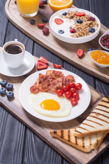 Frühstück mit Joghurt, Eiern, Beeren, Saft, Croissant und Marmelade