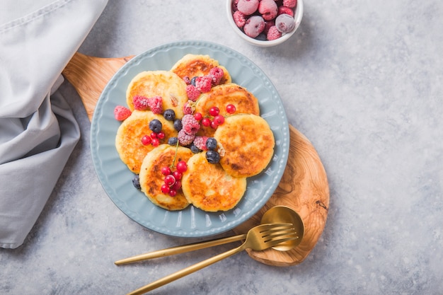 Frühstück mit Käsekuchen, frischen Beeren. Hüttenkäsepfannkuchen oder Quarkstückchen. Russisches Syrniki oder Sirniki