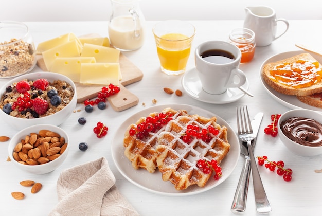 Frühstück mit Müsli-Beeren-Nüssen, Waffel, Toast, Marmelade, Schokoladenaufstrich und Kaffee