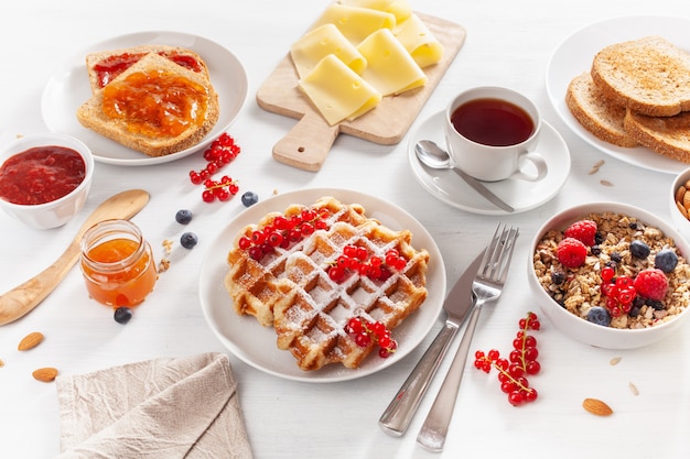 Frühstück mit Müsli-Beeren-Nüssen, Waffel, Toast, Marmelade, Schokoladenaufstrich und Tee