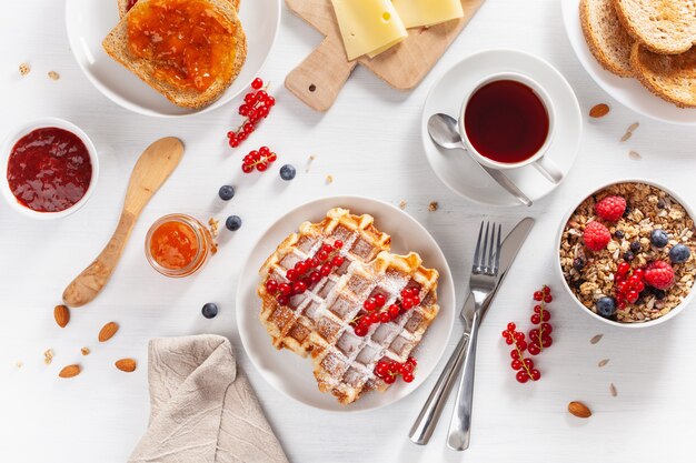 Frühstück mit Müsli-Beeren-Nüssen, Waffel, Toast, Marmelade und Tee. Draufsicht