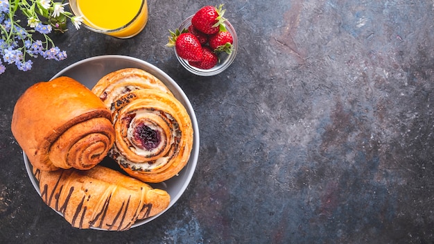 Frühstück mit Orangensaft, Erdbeere und Brötchen.