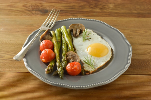 Frühstück mit Spargel, Spiegelei und Kirschtomaten. Holztisch.