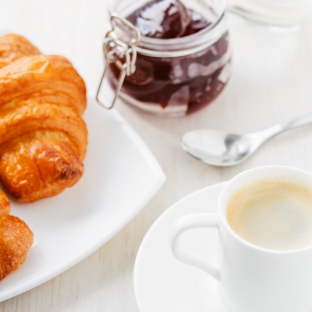 Frühstück mit Tasse Kaffee und Hörnchen mit Marmelade