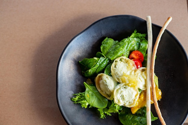 Frühstück morgens cremiges Omelett und Buratta-Käsesalat Avocado und grüne Blätter auf schwarzem p