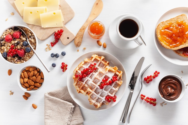 Frühstück Müsli Beeren Nüsse, Waffel, Toast, Marmelade, Schokoladenaufstrich und Kaffee. Draufsicht