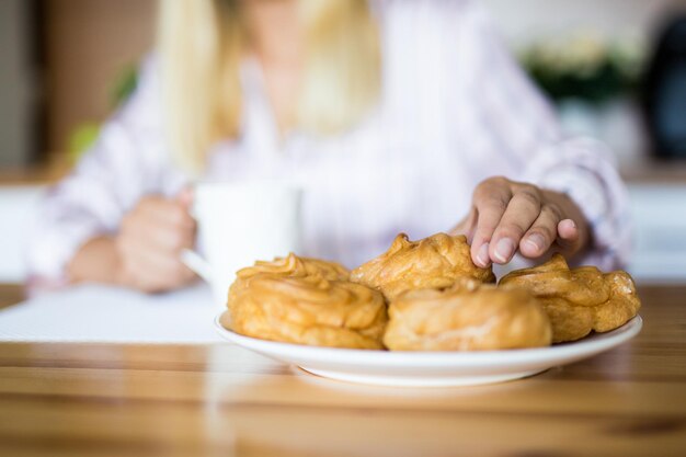 Frühstück - Nahaufnahme von weiblichen Händen, die süßes Gebäck vom Teller nehmen?