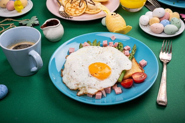 Frühstück oder Mittagessen mit Spiegelei, Toastbrot, grünem Spargel, Tomaten und Speck auf blauem Teller