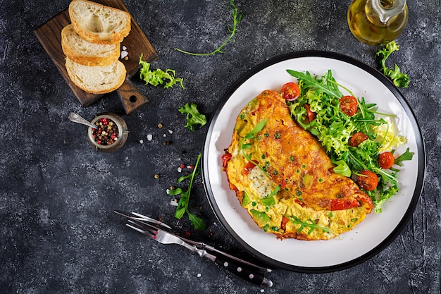 Frühstück. Omelett mit Tomaten, Avocado, Blauschimmelkäse und grünen Erbsen auf weißer Platte. Frittata - italienisches Omelett. Ansicht von oben