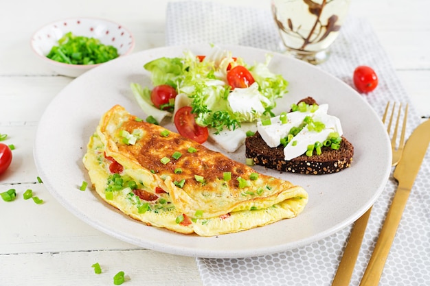 Frühstück. Omelette mit Tomaten, Käse, Frühlingszwiebeln und Sandwich mit Feta-Käse. Frittata - italienisches Omelett.