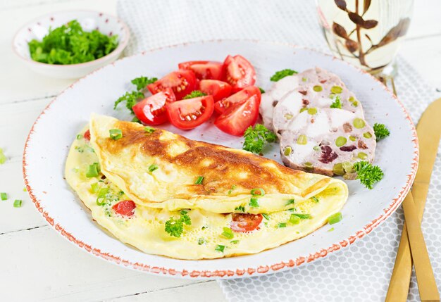 Frühstück. Omelette mit Tomaten, Käse und Fleischterrine oder Hackbraten auf weißer Platte. Frittata - italienisches Omelett. Keto-Diät.